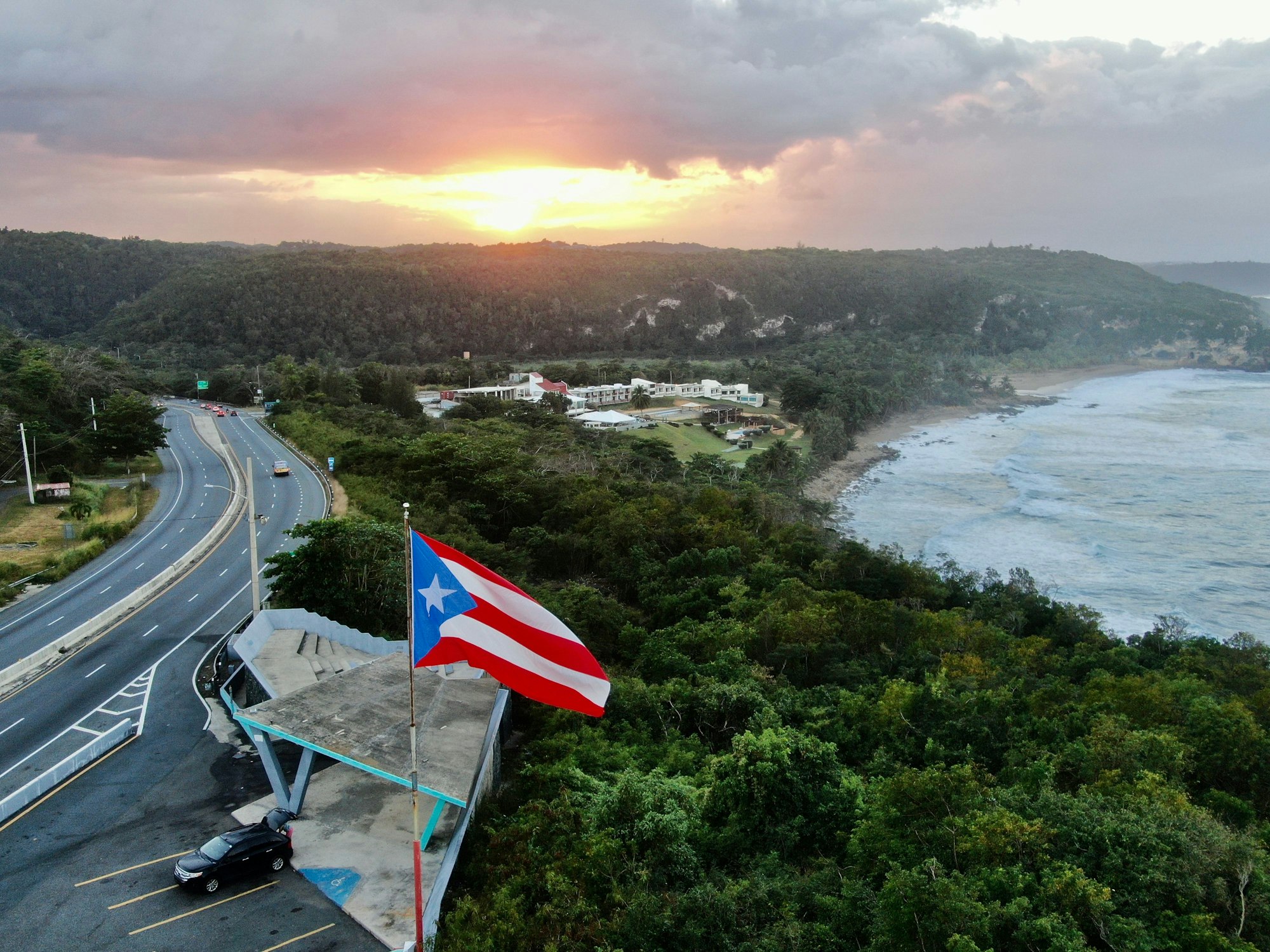 Aerial shot of the Flag of Puerto Rico waving in the air at a golden sunset in Quebradillas